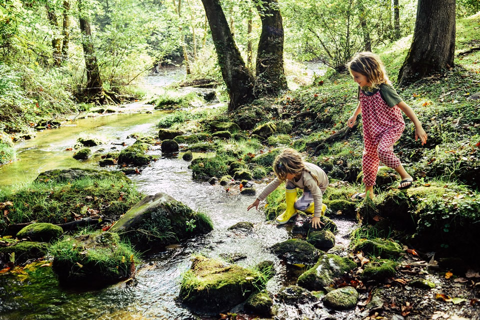 Two children playing near a stream