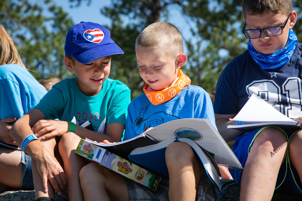 Three kids looking through camp materials